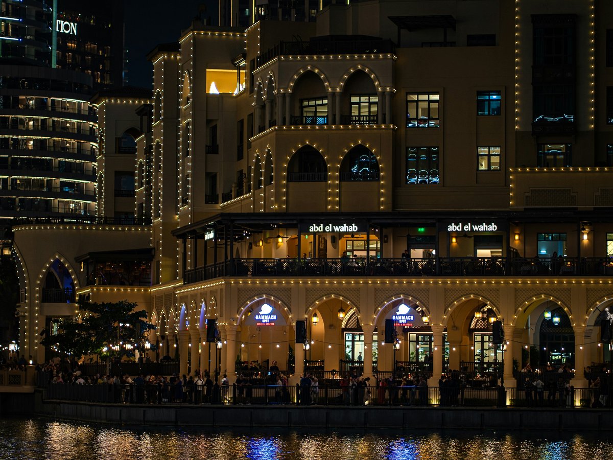 A large building with lights on it next to a body of water