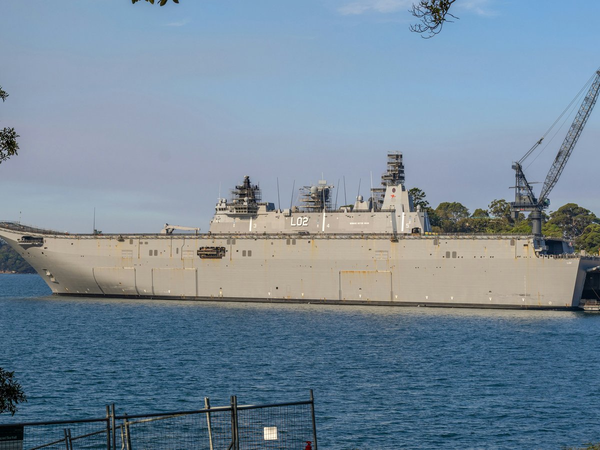A large gray naval ship docked in a harbor.
