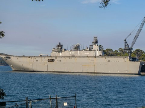 A large gray naval ship docked in a harbor.