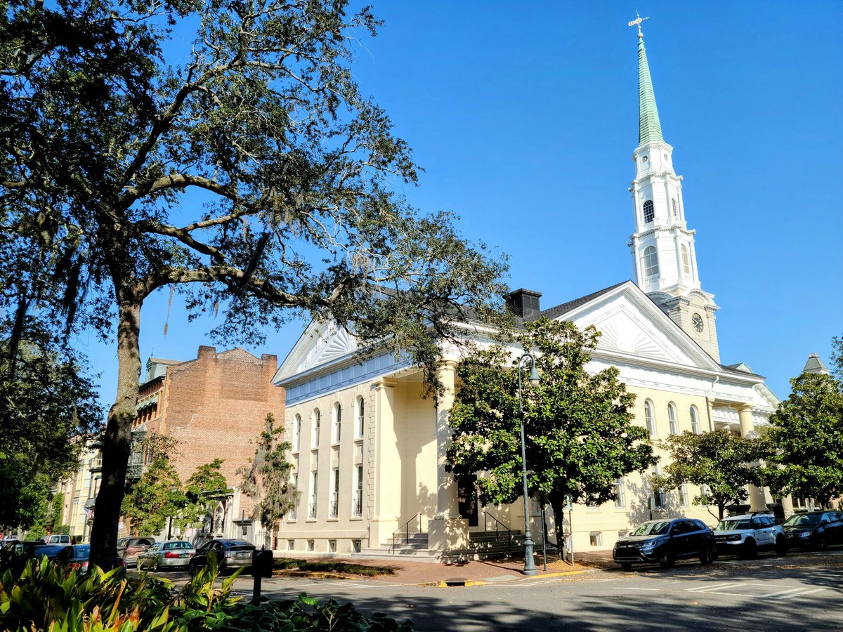 A church with a steeple and trees in front of it