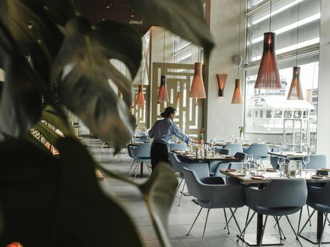woman in front on brown dining table and chairs inside building