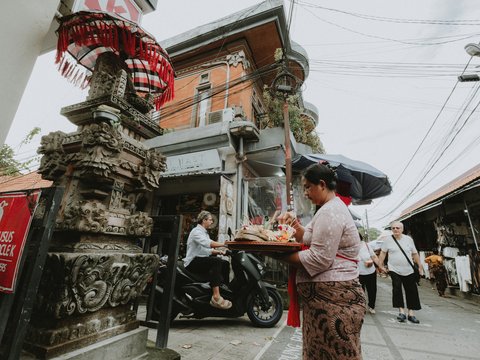 Woman carrying offerings in front of ornate temple entrance