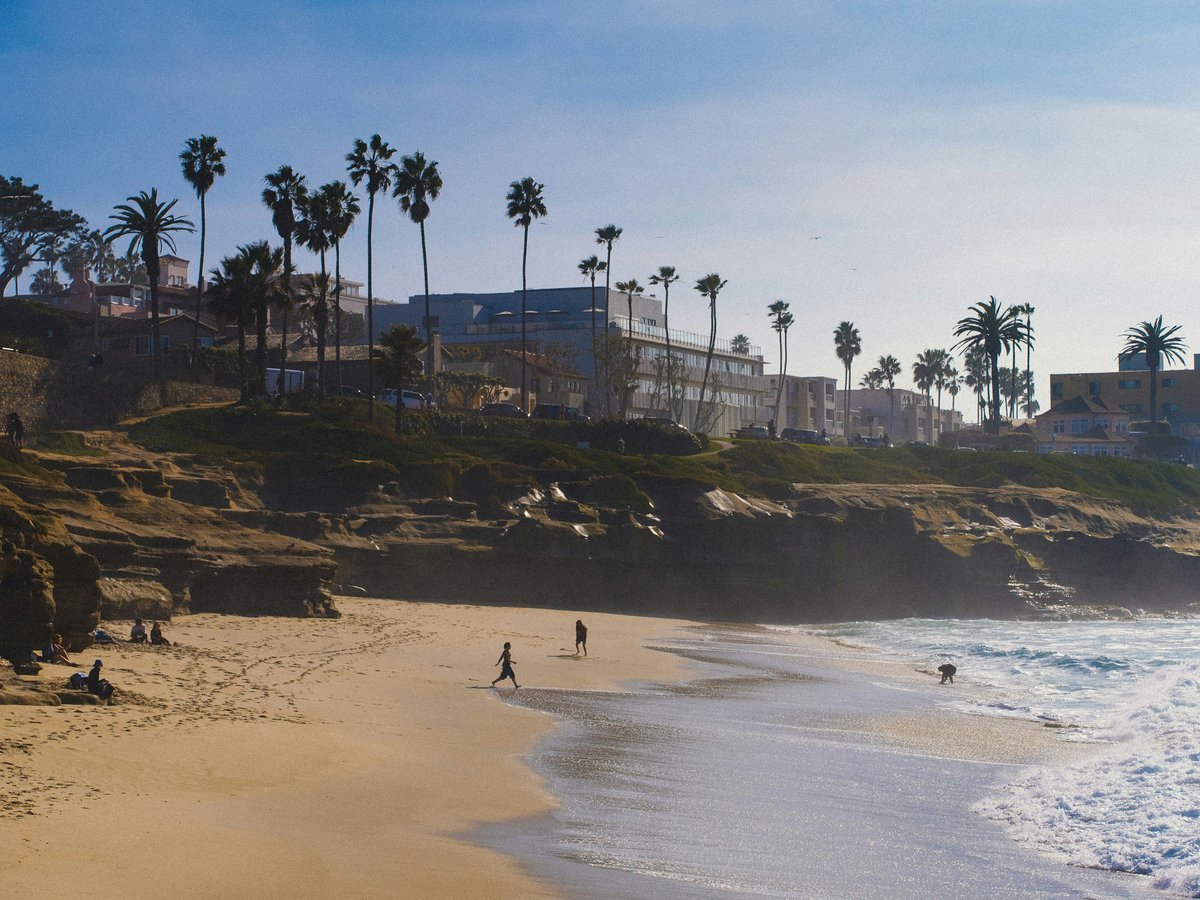 a couple of people walking along a beach next to the ocean