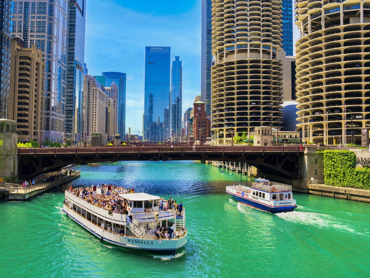 A river filled with lots of green water next to tall buildings
