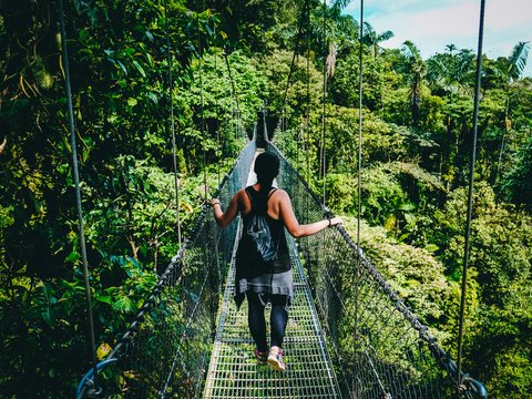 woman in black shirt and black pants standing on hanging bridge