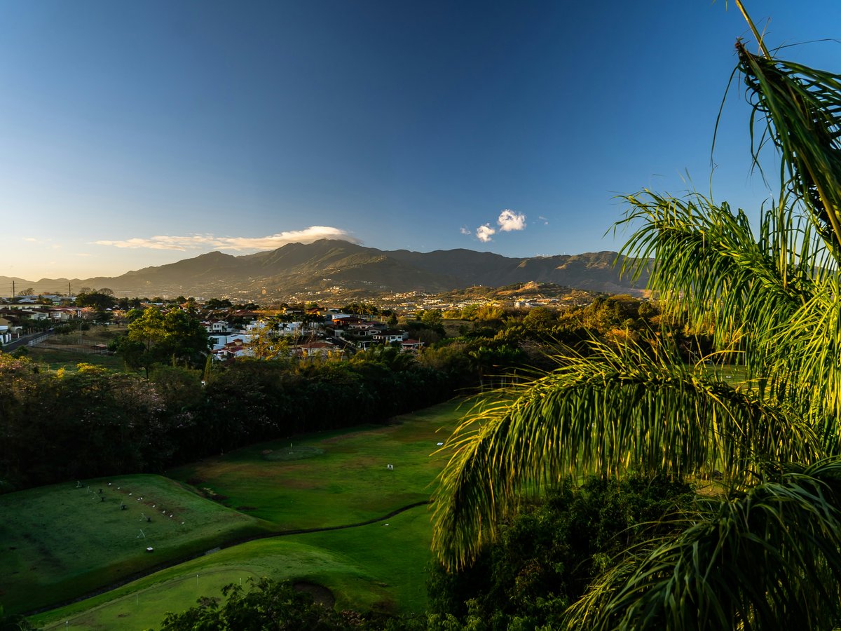 green grass field near green mountains under blue sky during daytime
