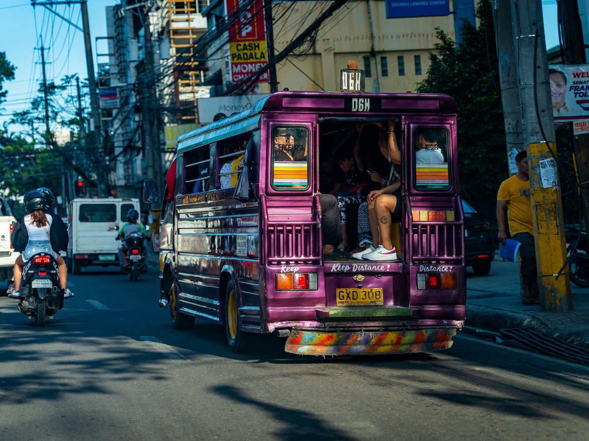 a purple bus driving down a street next to traffic