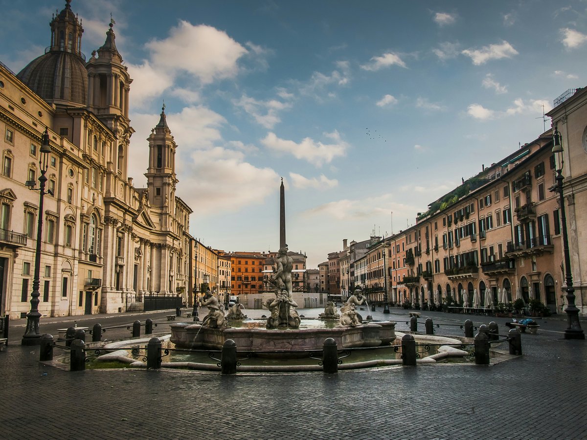 a canal with buildings along it with Piazza Navona in the background