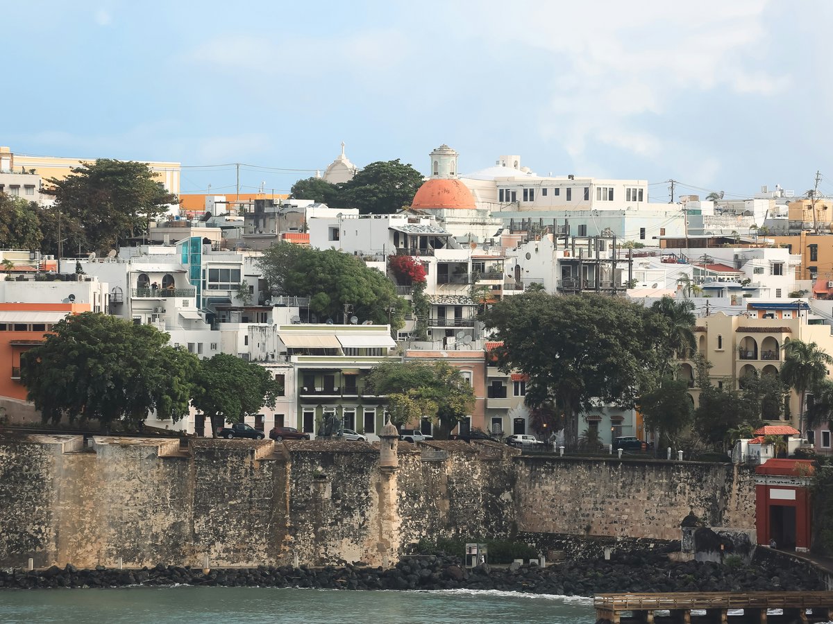 Historic buildings line a stone wall overlooking water