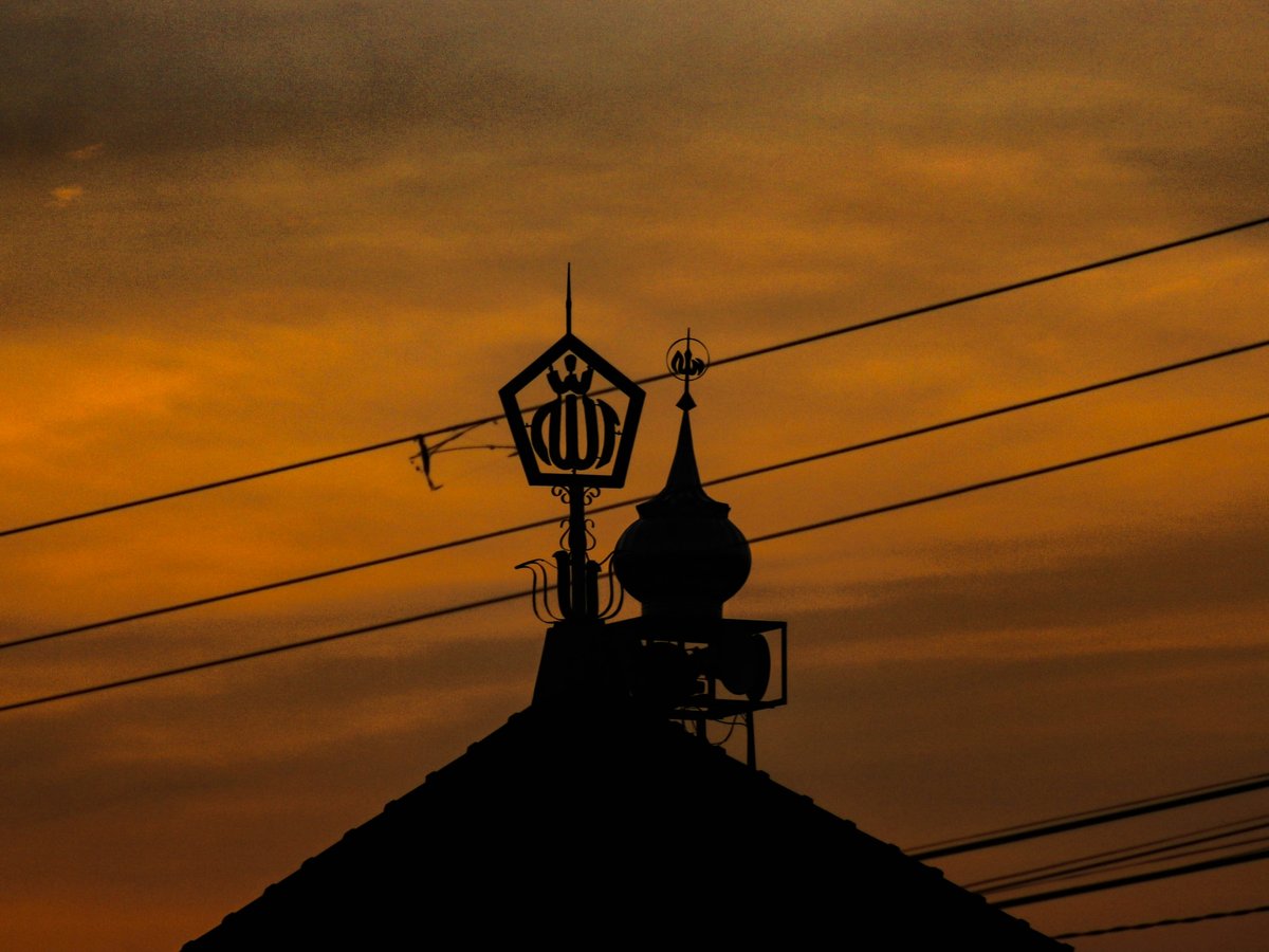 Silhouette of a mosque dome against sunset sky