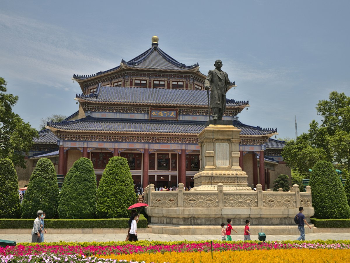 a statue of a man holding an umbrella in front of a building