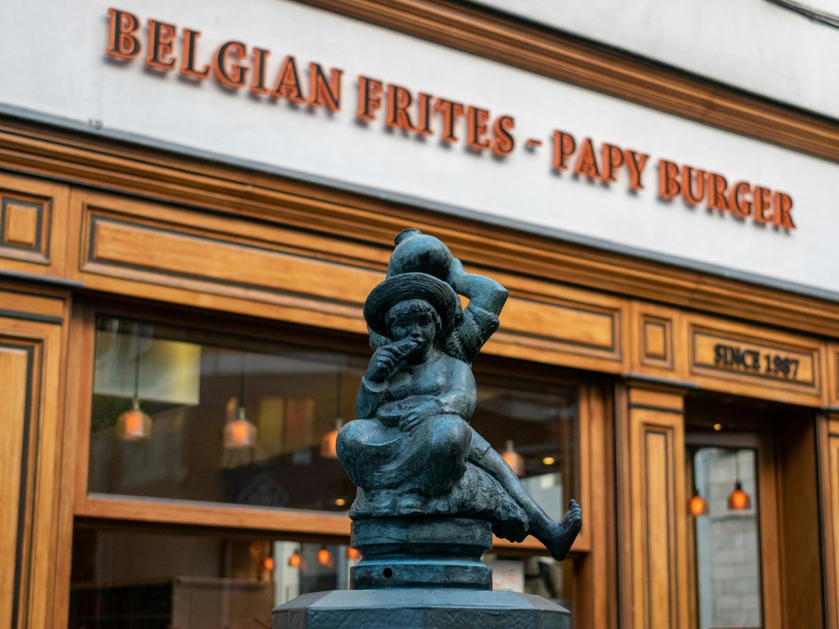 A statue of a person holding a hat in front of a building
