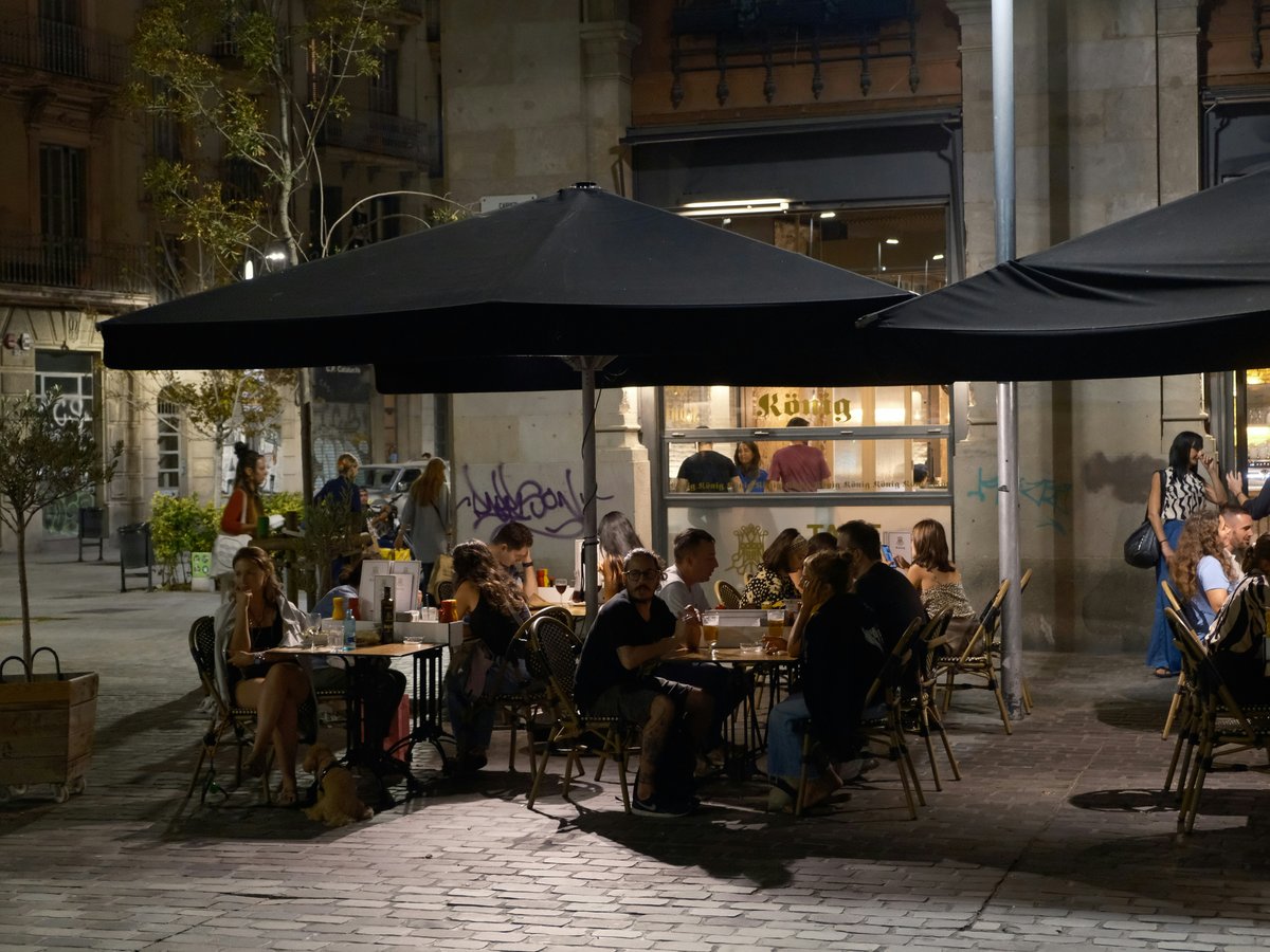 a group of people sitting at a table under black umbrellas
