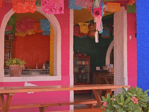 a pink and blue building with a wooden bench in front of it
