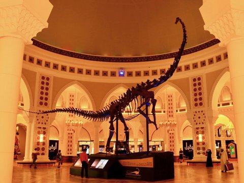 a dinosaur skeleton in a museum with people walking around