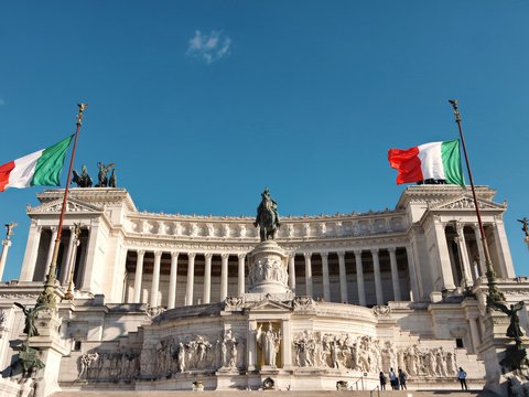 white concrete building with statue under blue sky during daytime
