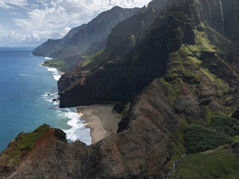 green and brown mountain beside body of water during daytime