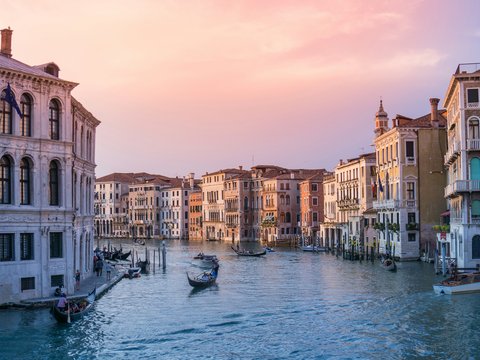 photo of gondolas on body of water between buildings